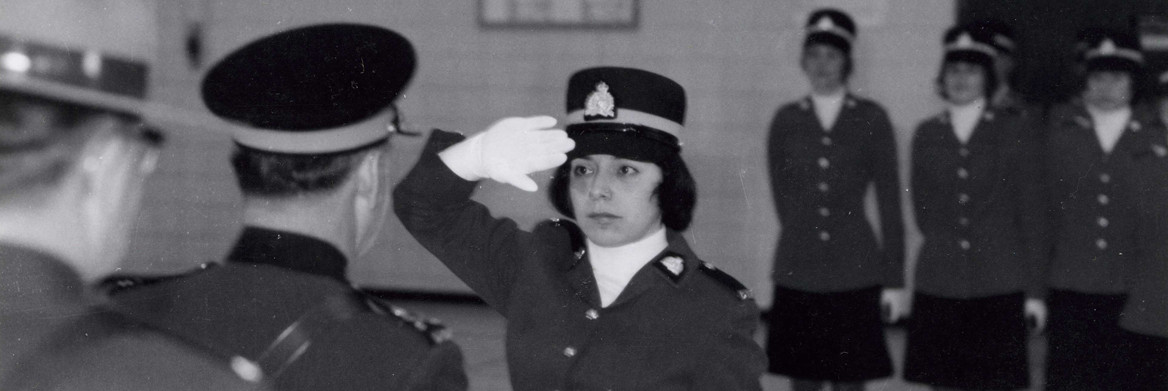 Portrait d'une policière de la GRC en uniforme bleu foncé, avec un drapeau canadien en arrière-plan.