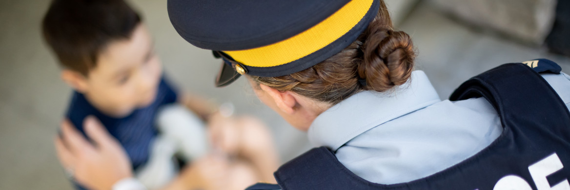 Female RCMP officer resting a hand on young boy's shoulder.