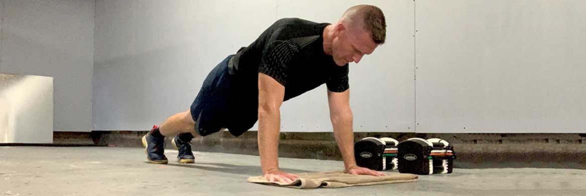 Un homme exécutant des pompes sur un tapis de caoutchouc lors d'un entraînement à la maison.
