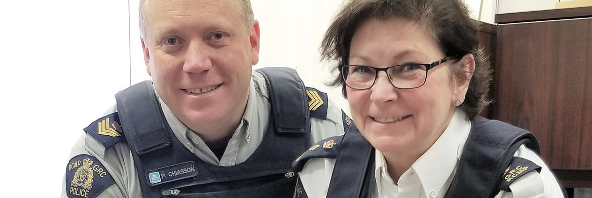 A male and a female RCMP officer smile while standing next to each other. 