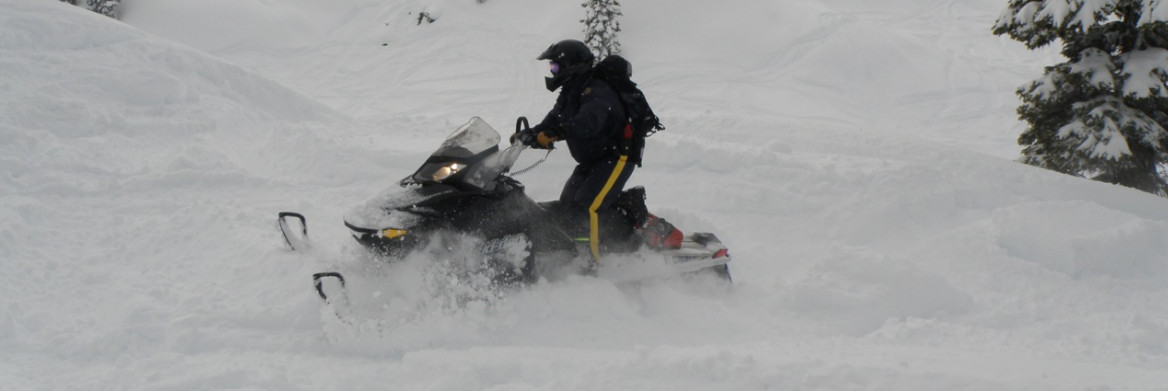 Un policier de la GRC conduisant une motoneige dans de la neige fraîche.