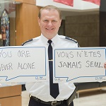 RCMP Deputy Commissioner Brian Brennan holding a Bell Let's Talk sign that reads in English 