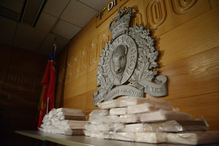 Photographie de 50 kilos de cocaïne présumée sur une table. Emblème de la GRC.