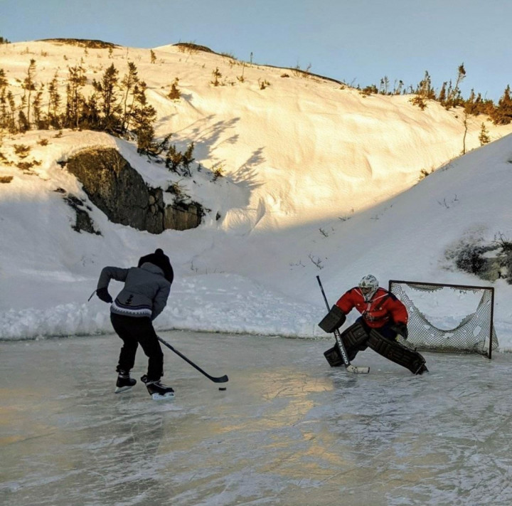 RCMP Constable Bergmark built an ice rink for the community of Hopedale. He is pictured here playing in goal while a player takes a shot on the net. 
