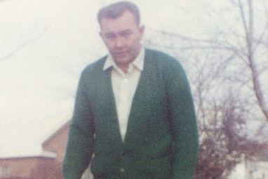 Une photographie non datée de Theodore Frederick Kampf portant une chemise à col de couleur claire et un pull cardigan vert.