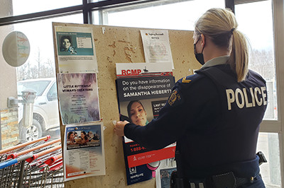 Photo of officer placing poster on a bulletin board