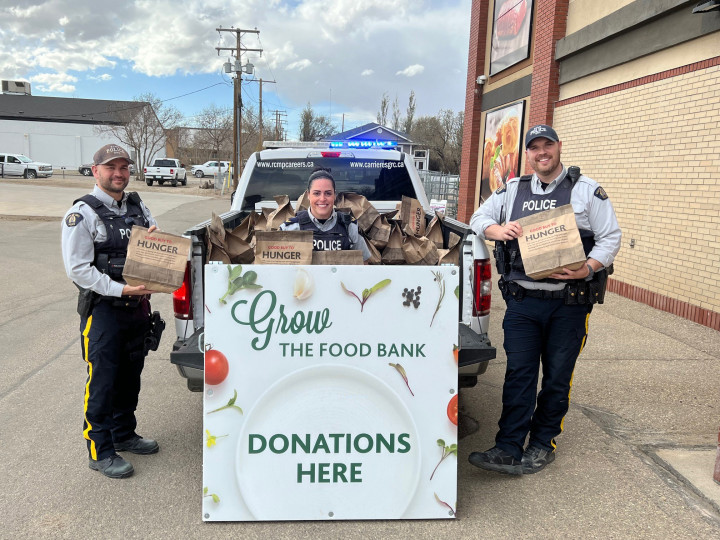 Trois policier à côté d'un camion de la GRC rempli de dons alimentaires pour la banque alimentaire de Kindersley et du district.