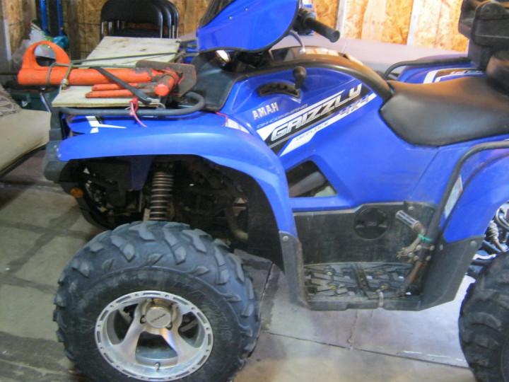 VTT bleu de marque et modèle Yamaha Grizzly garé à l'intérieur d'un garage ou d'une remise.