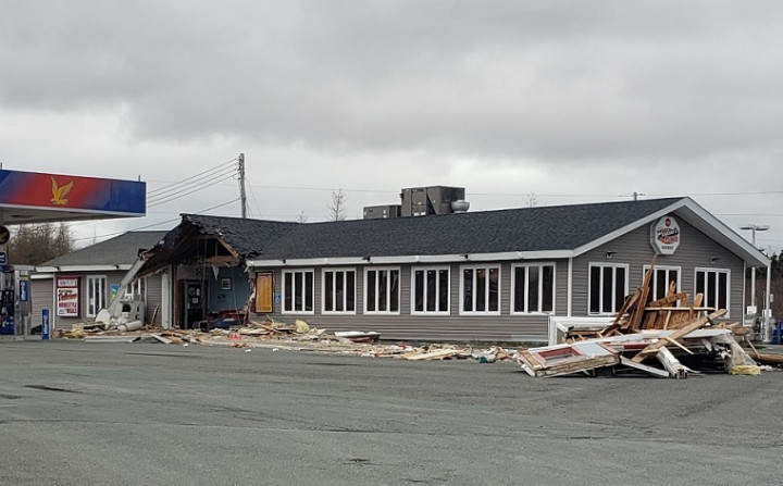 The Goobies Ultramar service station has severe damage to the roof and front entrance. Debris is scattered on the ground in front of the building.