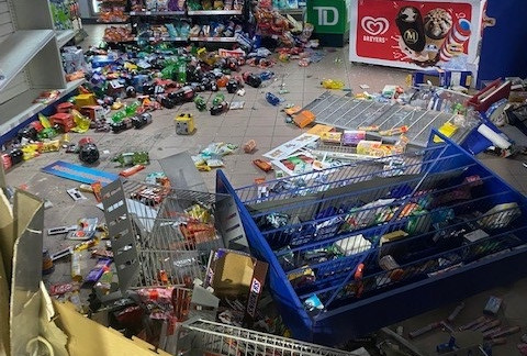 A number of shelves are tipped over with various food items across the floor inside the Ultramar Gas Station in South River.