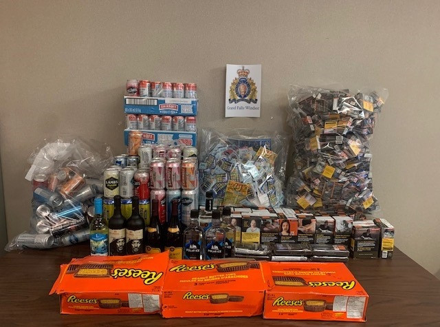 A number of items, including five bottles of wine, three bottles of Polar Ice Vodka, cases of canned coolers, a bag of various lottery tickets, a bag of packaged cigarettes, various of cartons of cigarettes and three cases of Reese's Peanut Butter Cups, are displayed on a table.