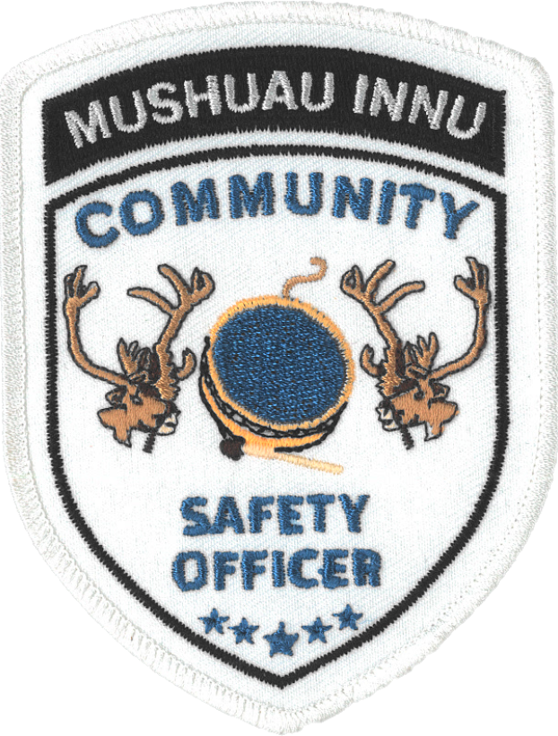 Insigne blanc sur lequel sont brodés les mots « Mushuau Innu Community Safety Officer » et deux caribous, un tambour ainsi que cinq étoiles. 