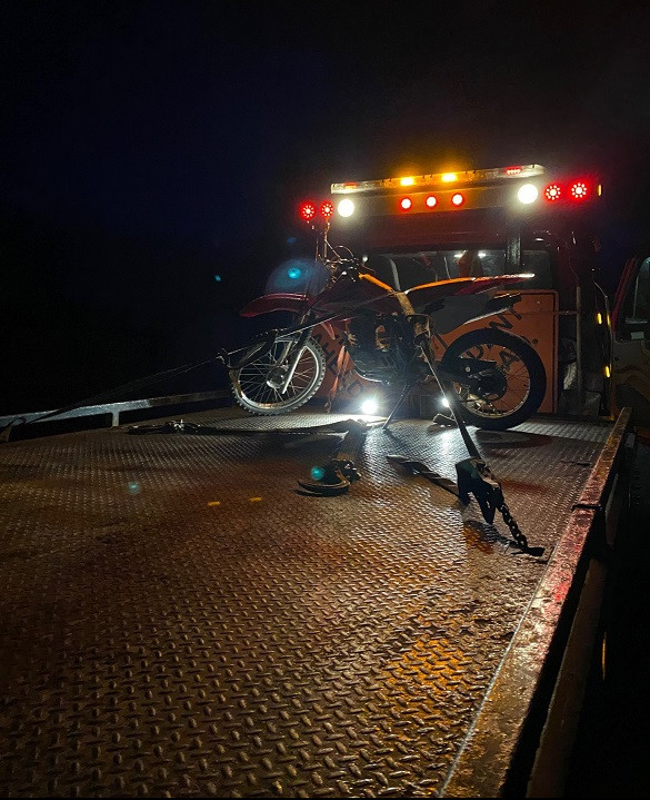 Photo prise le soir d'une moto hors route attachée debout à l'arrière d'une dépanneuse.