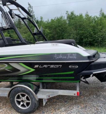 The back end of a large black sport boat with neon green painted accents is shown. There is also grey text on the boat which reads 