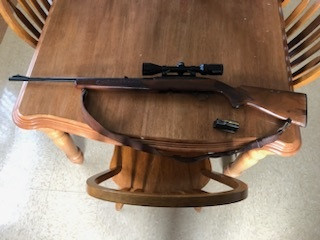 Carabine Winchester 100 de calibre .308 avec viseur sur une table en bois.