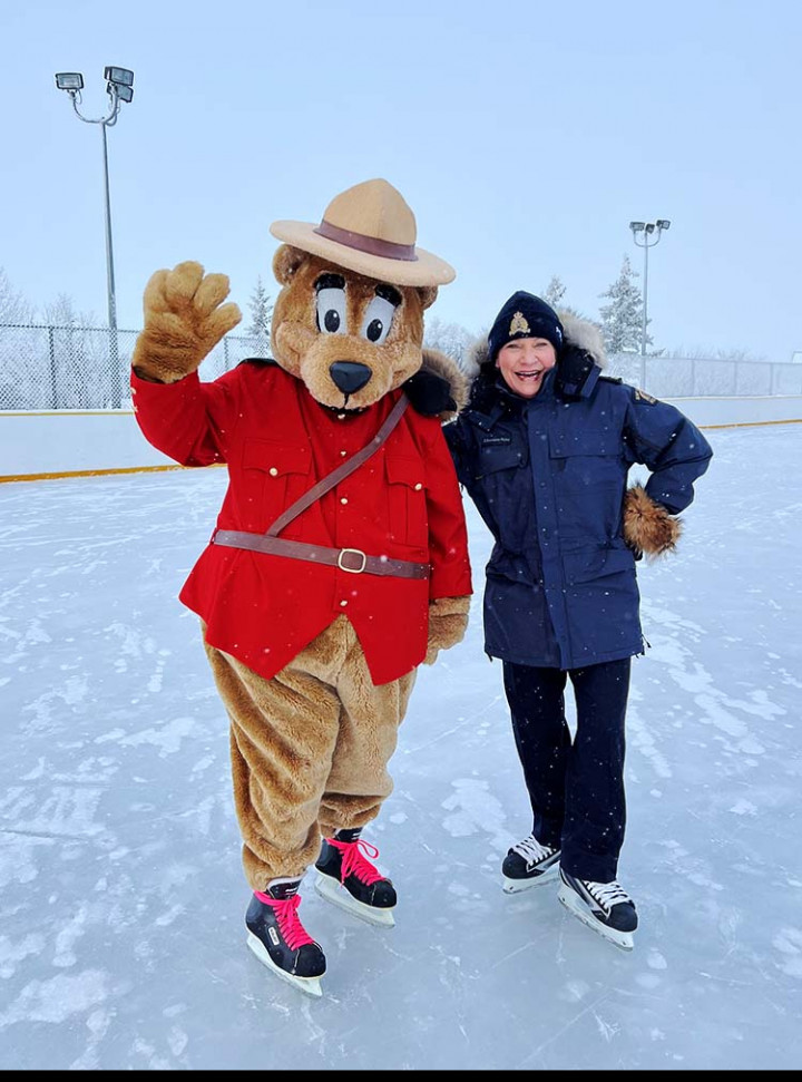 The CO and Safety Bear stand outside an outdoor skating rink.