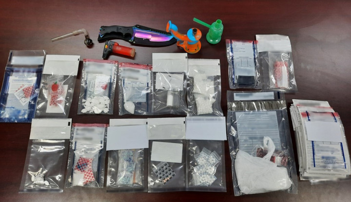 Seized drugs, paraphernalia and weapons laid out on a table
