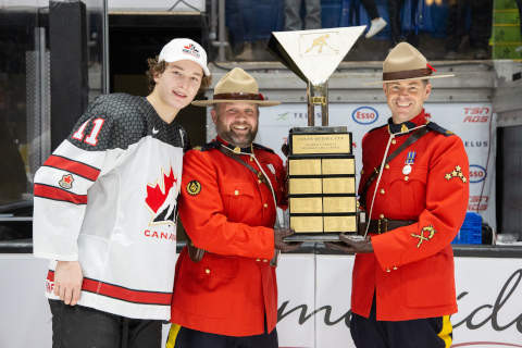 (De gauche à droite) Matthew Schaefer, défenseur d'Équipe Canada Blanc, l'agent Lorenz Sanders et le sergent d'état-major Michael Robinson avec le trophée du hockey mondial U-17