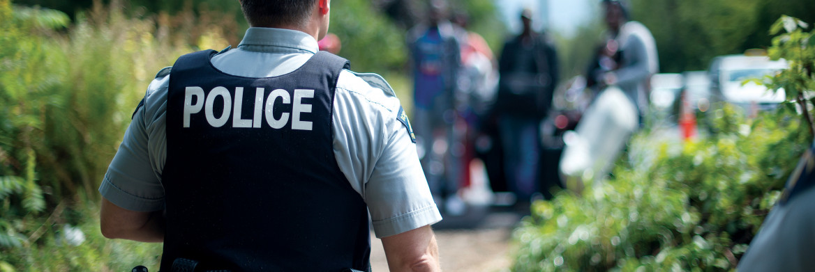 Un policier fait face à un groupe de personnes marchant vers lui.