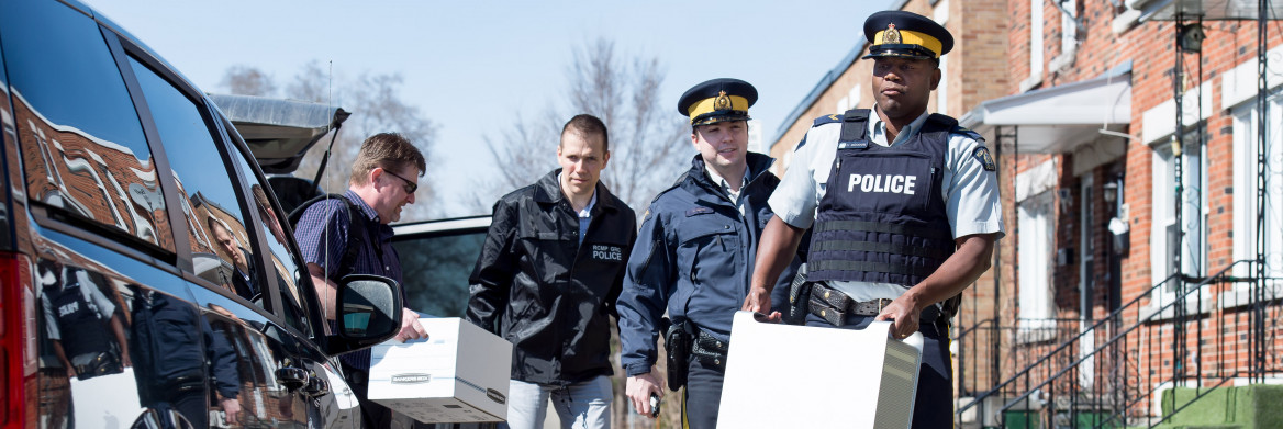 Quatre policiers transportant du matériel informatique dans la rue.