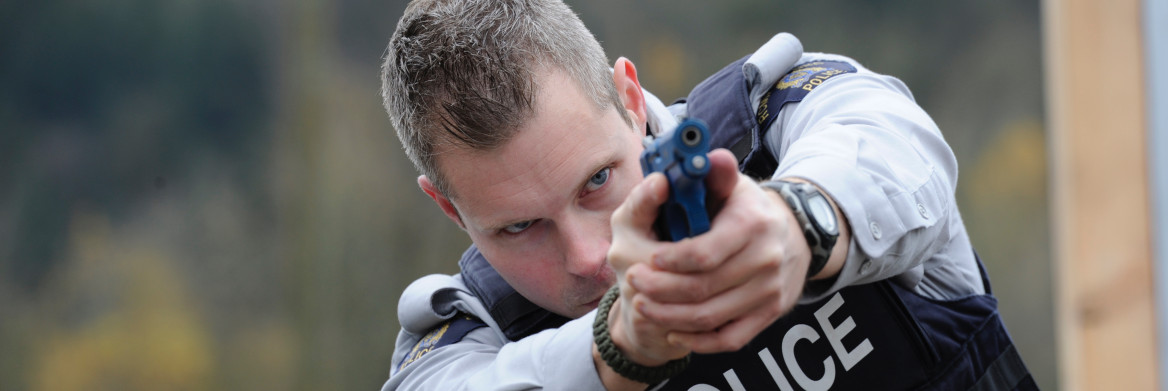 Police officer points training pistol.