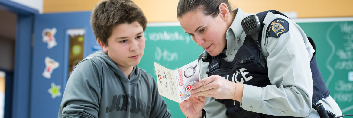 Female police officer interacting with boy in a classroom.