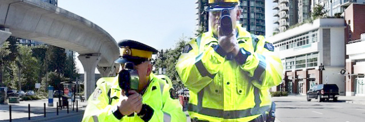 Un policier-épouvantail et un vrai policier de la GRC pointent en avant leur détecteur laser qu'ils tiennent à la hauteur du torse.