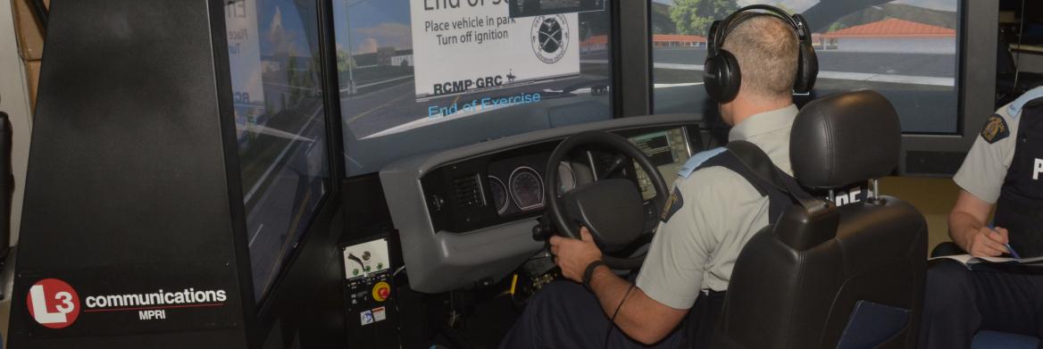 Les mains sur un volant, un cadet est assis à une console de formation en réalité virtuelle.