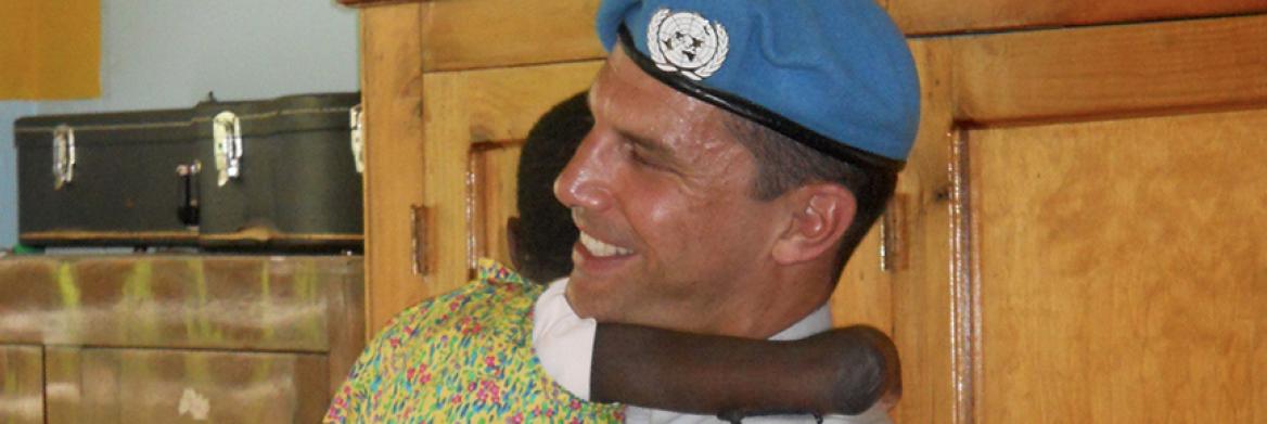Le visage souriant, un policier de la GRC reçoit un câlin d'une jeune haïtienne.