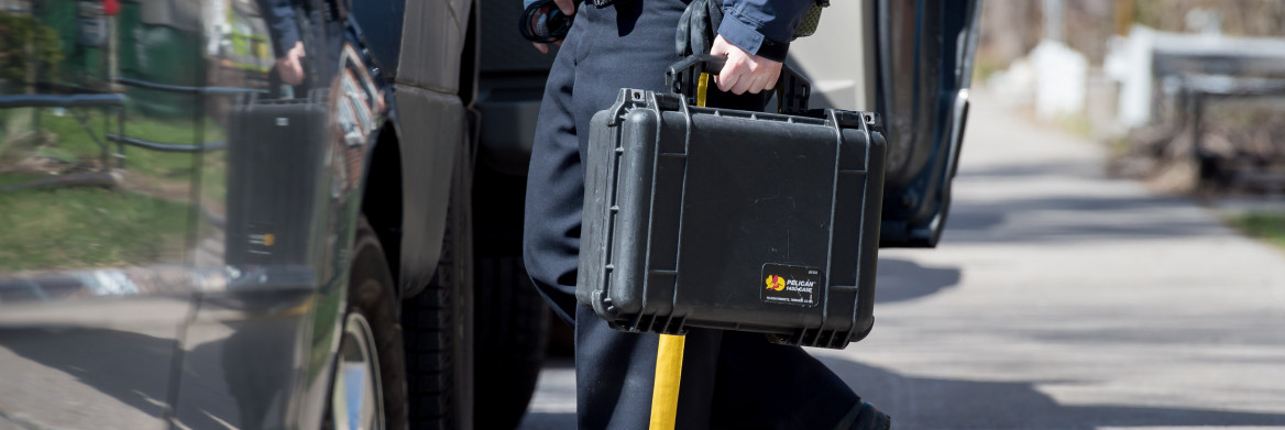 Police officer carrying hard case.