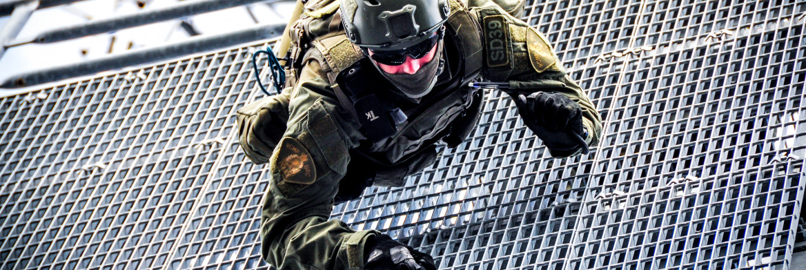 An RCMP Emergency Response Team member climbs down a metal grate during a training exercise.
