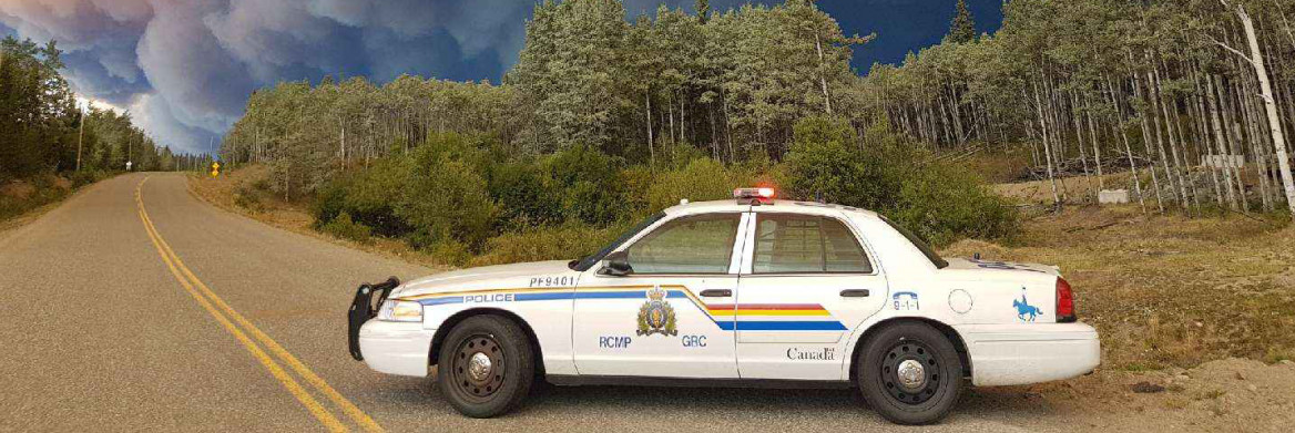 RCMP car on a highway with billowing smoke in the sky.