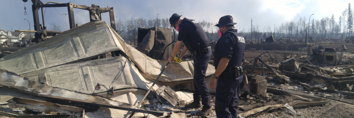 Deux policiers sur les ruines d'une maison brûlée.