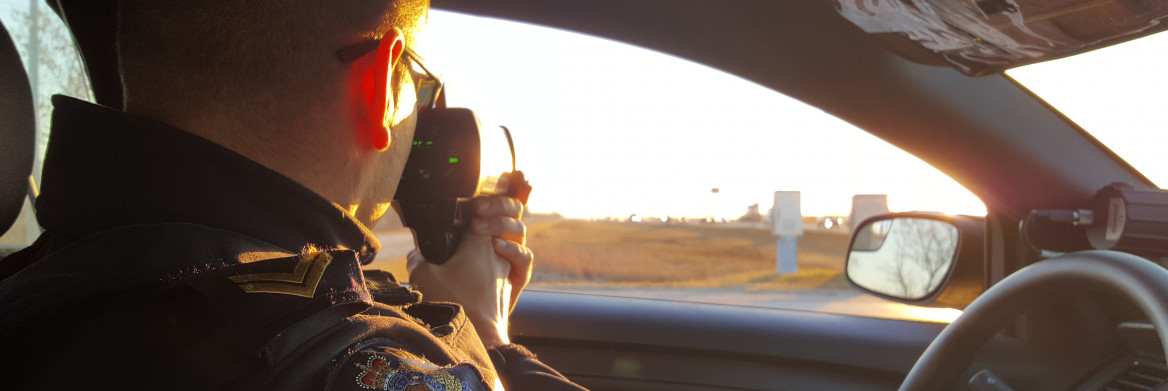 A RCMP officer sits in a car and measures the speed of passing cars.