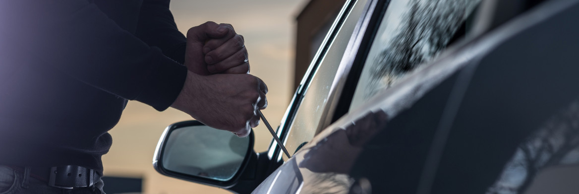 Man trying to break into car with screwdriver.