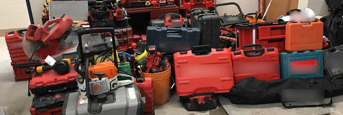 A large number of tools, mostly in carrying cases, are displayed inside a commercial garage space.