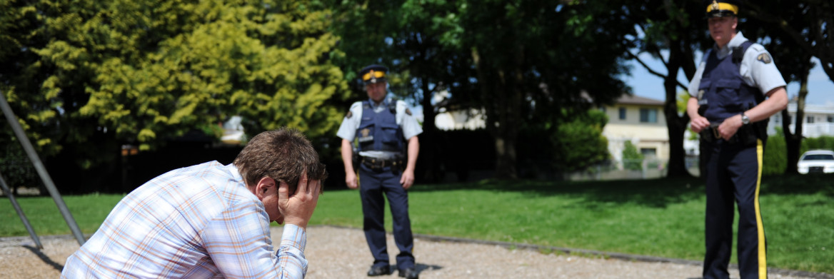 Deux policier s'approchent d'une personne en détresse assise dehors la tête entre les mains.