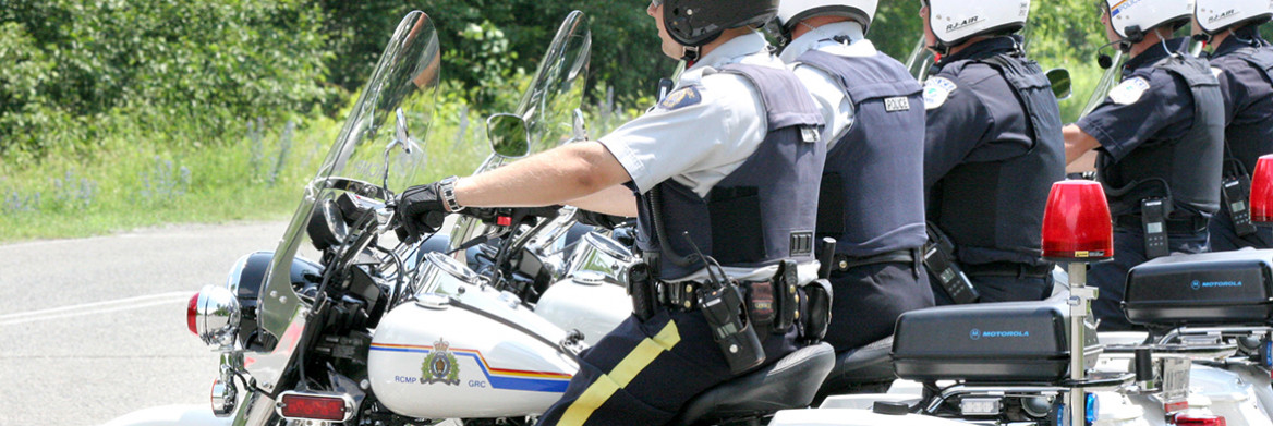 A group of RCMP officers sit on police motorcycles. 