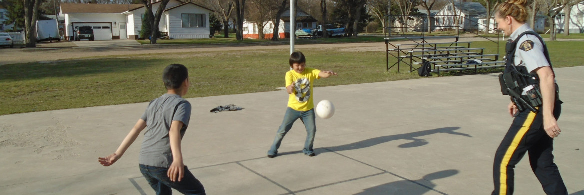 Female police officer playing ball with two children.