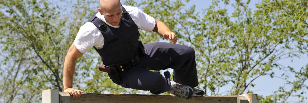 Un cadet en uniforme escalade une clôture.