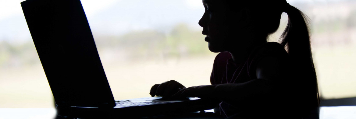 Silhouette d'une fillette devant un ordinateur portable.