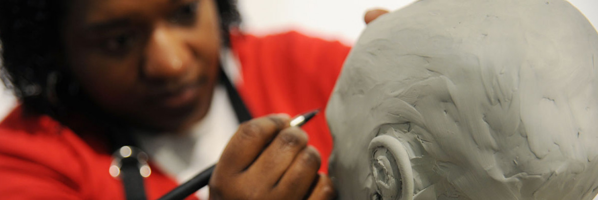 An artist uses a stylus to add fine details to the sculpture.