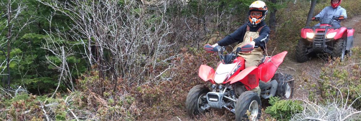 Two young people riding ATVs.
